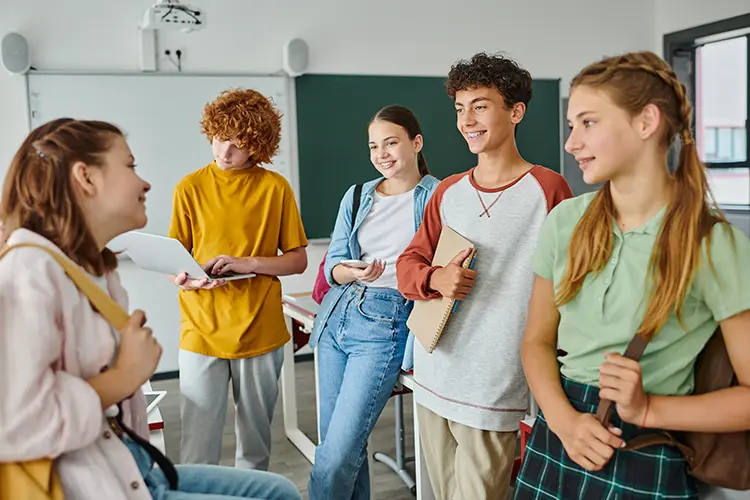 Gruppe von fünf Jugendlichen steht in einem Klassenzimmer zusammen als Symbol für den MHFA Ersthelfer-Kurs Youth.